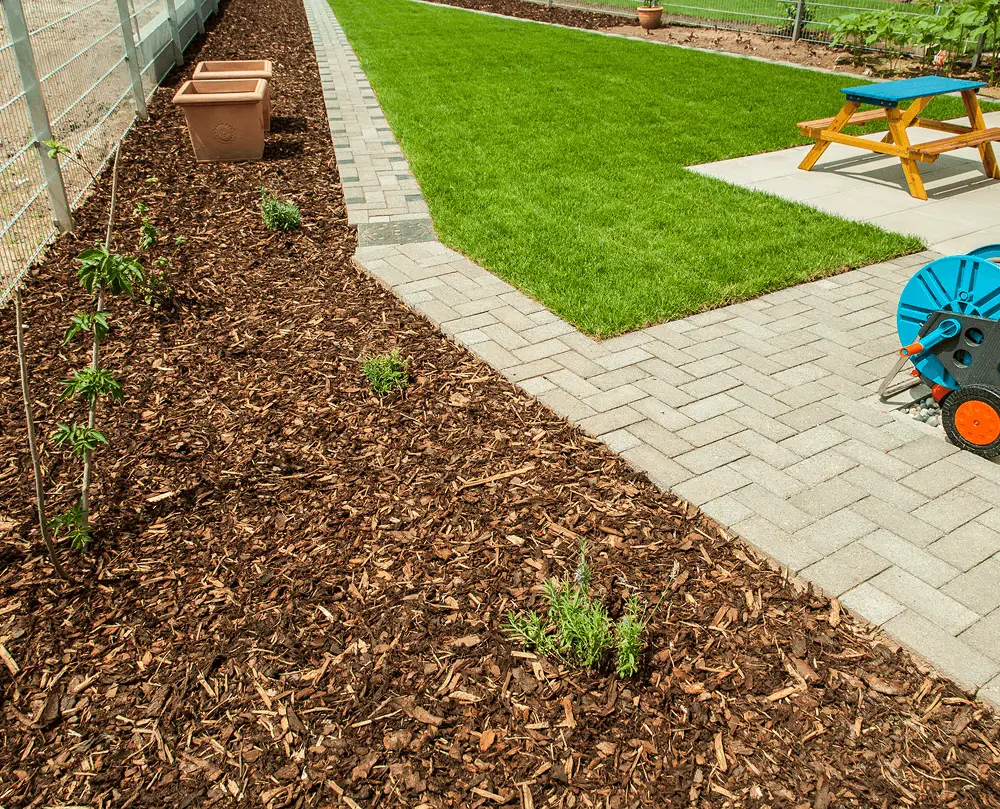 Garden with grass, mulch, and picnic table.